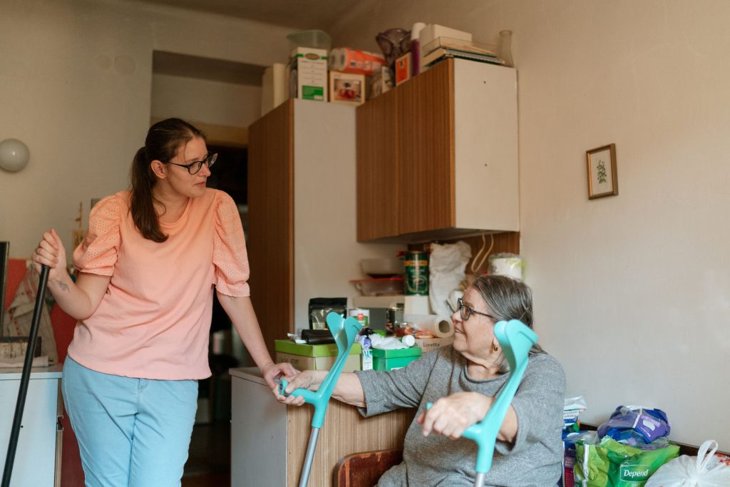 Pflegekraft begleitet Seniorin mit Gehhilfe in der Wohnung