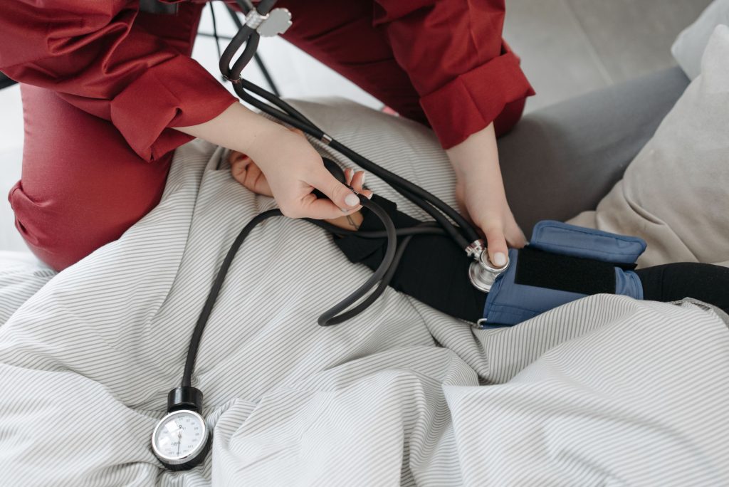 Mobile Krankenpflege kontrolliert den Blutdruck im Pflegebett